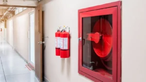 Wall-mounted fire extinguisher with hose, providing manual fire suppression support in commercial buildings