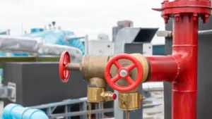 Fire department connection (FDC) with red valves, part of a commercial fire suppression system for emergency water supply.