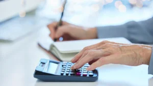 Close-up of hands using a calculator with fire alarm system documents