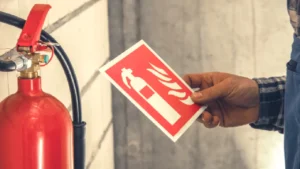 Professional performing a fire extinguisher inspection in an office or school, highlighting routine maintenance and NFPA-compliant safety practices